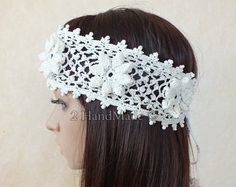 May include: White crocheted headband with delicate floral accents. The headband is tied at the back with a white ribbon.