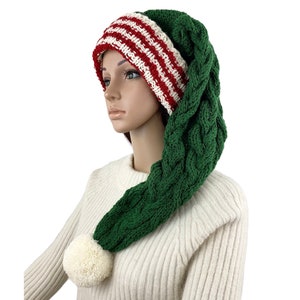 May include: A green and white knit elf hat with a long, braided tail and a white pom-pom. The hat's brim is striped red and white. This festive hat is perfect for holiday celebrations and costumes.
