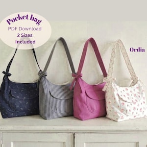 Könnte beinhalten: Vier Umhängetaschen mit einer Vordertasche und einer Schleife am Träger. Die Taschen sind marineblau mit kleinem Blumenmuster, grau mit weißen vertikalen Streifen, einfarbig magenta und weiß mit rosa Blumenmuster. Der Text lautet Pocket bag.