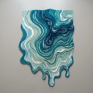 May include: An abstract rug with a flowing, water-inspired design. The rug uses shades of blue, teal, and white to create depth and movement. The edges have a melted or dripping effect, enhancing the artistic look. The rug's dimensions are not visible.