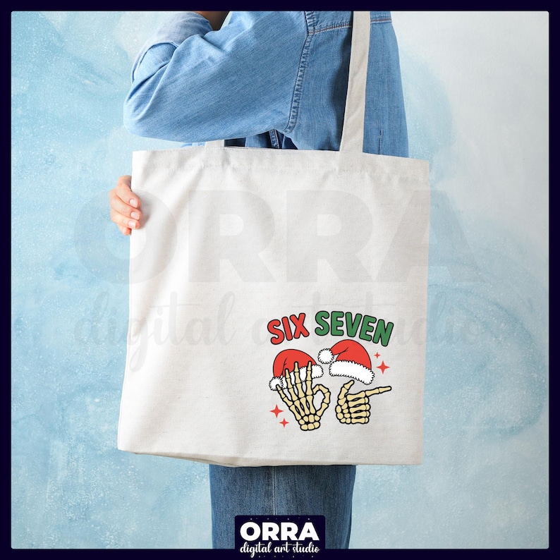 May include: A white tote bag with a graphic that says "SIX SEVEN" in red and green. The graphic features two skeleton hands wearing Santa hats, one making an "okay" sign and the other pointing.