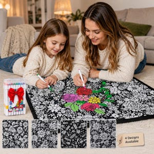 Pu&ograve; includere: Un tappetino in tessuto quadrato con un motivo floreale in bianco e nero da colorare, accompagnato da una custodia in plastica trasparente con pennarelli colorati e un fiocco rosso. Il tappetino mostra disegni floreali e un cartello indica 4 Designs Available.