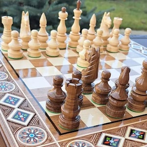 Könnte beinhalten: Ein Schachspiel aus Holz mit einem polierten Brett, das mit geometrischen und floralen Mustern in Blau, Rot und Weiß eingelegt ist. Das Set enthält geschnitzte Schachfiguren aus hellem und dunkelbraunem Holz, darunter Türme, Springer, Läufer und Bauern.