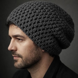 May include: A dark gray, hand-knitted beanie hat with a textured, raised pattern. The hat is made of a soft, thick yarn and has a relaxed fit. The beanie is a stylish accessory for cold weather.