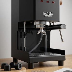 Puede incluir: Una máquina de espresso Gaggia Classic negra con tres interruptores, una boquilla de vapor y el nombre de la marca. La imagen también muestra un juego de cuatro pies de polímero negros y un catálogo de productos.
