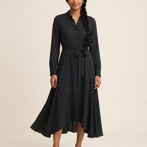 May include: A black midi-length shirt dress featuring a white polka dot pattern, a collared neckline, long sleeves with buttoned cuffs, a button-down front, and a matching fabric tie belt at the waist. The skirt has a high-low hemline.