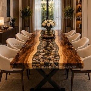 Puede incluir: Una mesa de comedor rectangular con borde de madera natural y una incrustación central de piedras de río lisas y multicolores en resina transparente, sobre una base de metal negro en forma de X, rodeada por diez sillas de color crema.