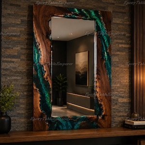 May include: A rectangular wall mirror featuring a natural live-edge wood frame with a vibrant emerald green epoxy resin inlay that flows along the sides. The mirror surface reflects a room interior, and the frame has a smooth, polished finish.