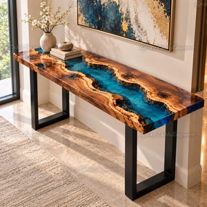 May include: A long console table featuring a live edge wood slab with a central river of translucent blue epoxy resin. The table is supported by two black metal U-shaped legs and displays a natural wood grain pattern with knots.