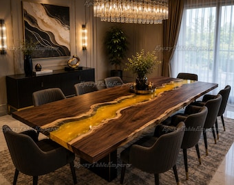 May include: A large, rectangular wooden dining table with a river of yellow epoxy resin down the centre. The table is surrounded by grey upholstered chairs. A modern chandelier hangs above the table, illuminating the room.