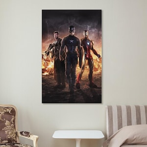 May include: A framed poster featuring three superheroes: Captain America, Iron Man, and Thor. The heroes are standing in front of a fiery background. Captain America is in the center, holding a shield. Iron Man is on the right, and Thor is on the left.