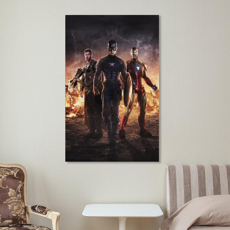 May include: A framed poster featuring three superheroes: Captain America, Iron Man, and Thor. The heroes are standing in front of a fiery background. Captain America is in the center, holding a shield. Iron Man is on the right, and Thor is on the left.