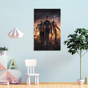 May include: A framed canvas print featuring three superheroes: Captain America, Thor, and Iron Man. The heroes are walking towards the viewer against a fiery background. Captain America holds his shield.