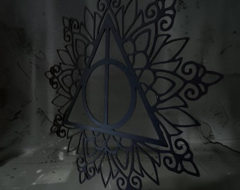 May include: A black, flat, laser-cut wall decoration featuring the Deathly Hallows symbol centered within an intricate, symmetrical mandala-style floral pattern with pointed petals and swirling filigree details throughout the design.