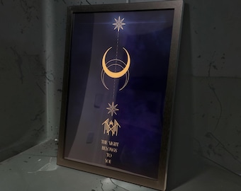 May include: A framed vertical print featuring a dark blue background with gold celestial graphics including a star, a crescent moon, and a geometric symbol. The text "THE NIGHT BELONGS TO YOU" is printed in gold lettering at the bottom of the artwork.