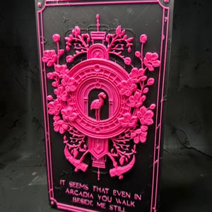 May include: A rectangular black plaque featuring a raised neon pink relief design. The center displays a flamingo inside an arched frame surrounded by floral motifs and two scythes. The text reads: IT SEEMS THAT EVEN IN ARCADIA YOU WALK BESIDE ME STILL.