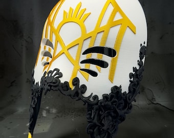 May include: A white helmet featuring a prominent yellow sun-like emblem and geometric cutouts. The lower edge is adorned with intricate, raised black filigree detailing, and the bottom tips of the helmet are accented with sharp yellow points.