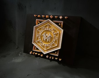 May include: A dark brown rectangular plaque featuring a layered, gold-colored hexagonal emblem with white geometric line work and a central symbol. Small, individual white characters are arranged in rows above and below the central hexagon.