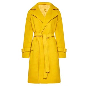 Könnte beinhalten: Ein leuchtend gelber Trenchcoat mit passendem Bindegürtel. Der Mantel hat einen klassischen Reverskragen, lange Ärmel mit Manschettendetails und einen Bindegürtel in der Taille. Der Mantel ist aus einem weichen, strukturierten Stoff gefertigt.