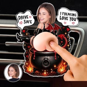 Peut inclure: Un désodorisant de voiture en acrylique personnalisé représentant un personnage de diable avec un visage réaliste, assis dans un chaudron noir. Le texte indique DRIVE SAFE et I FREAKING LOVE YOU. Le design inclut des cœurs rouges et des flammes.
