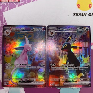 Op de afbeelding: Twee holografische Pokemon-ruilkaarten met Espeon ex met 260 HP en Umbreon ex met 270 HP. Espeon is roze met de Solar Beatdown-aanval, terwijl Umbreon zwart is met gele ringen en de Lunatic Claw-aanval. Beide kaarten tonen gedetailleerde illustraties en spelstatistieken.