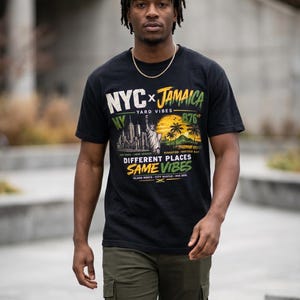 Pode incluir: Camiseta preta com um gráfico que diz "NYC x Jamaica Yard Vibes". A camisa apresenta imagens do horizonte da cidade de Nova York, da Estátua da Liberdade e de uma cena de praia tropical. A pessoa está usando calças cargo verde-oliva.