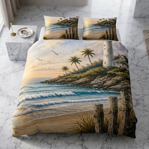 Pode incluir: Um conjunto de roupa de cama com uma cena costeira que inclui um farol, palmeiras e uma praia de areia com postes de madeira. A capa de edredão e as duas fronhas a condizer mostram um pôr do sol sobre o oceano com gaivotas no céu.