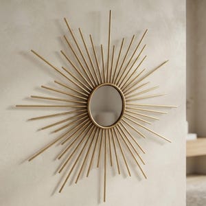 May include: A circular wall mirror featuring a gold-toned frame with numerous thin, radiating metal spokes of varying lengths that extend outward from the center, creating a sunburst design with a reflective glass surface in the middle.