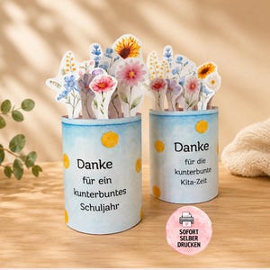 May include: Two cylindrical paper containers decorated with yellow dots and watercolor floral cutouts. The left container reads "Danke für ein kunterbuntes Schuljahr" and the right reads "Danke für die kunterbunte Kita-Zeit". A pink circular badge says "SOFORT SELBER DRUCKEN".