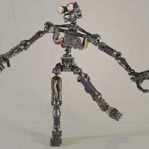 Puede incluir: Una figura de acción de robot metálico con un marco esquelético expuesto, que presenta articulaciones de color gris oscuro, cableado interno visible en amarillo y morado, y dos ojos circulares claros dentro de una estructura de cabeza mecánica.
