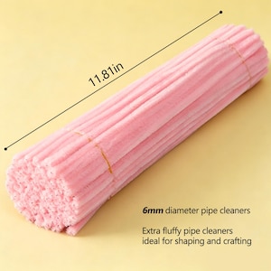 May include: A bundle of light pink pipe cleaners with a fuzzy texture. The bundle measures 11.81 inches in length and features individual pipe cleaners with a 6mm diameter. The text 6mm diameter pipe cleaners and Extra fluffy pipe cleaners are visible.