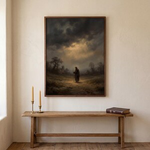 May include: A framed print of a dark, dramatic landscape painting. A figure with a staff walks down a path toward a light in the distance. The painting is framed in a dark wood frame and hangs above a wooden bench.