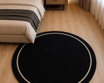 Tappeto rotondo in lana nero avorio, trapuntato a mano, minimalista, per un arredamento moderno.