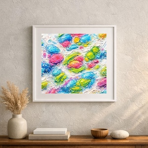 Può includere: Dipinto astratto incorniciato con bordo bianco. L'opera presenta una superficie strutturata con forme arrotondate colorate nelle tonalità di blu, rosa, verde e giallo. Il dipinto è esposto su un tavolo di legno con un vaso e una ciotola.