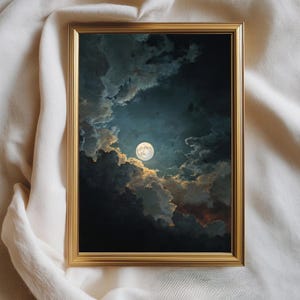 Può includere: Una stampa incorniciata raffigurante un paesaggio notturno con una luna piena che sbuca attraverso nuvole scure e drammatiche. L'opera d'arte ha una cornice color oro ed è ambientata su uno sfondo di tessuto color crema.