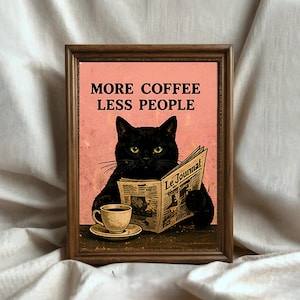 Può includere: Stampa artistica incorniciata con un gatto nero che legge un giornale con il titolo "Le Journal". La stampa ha uno sfondo rosa con il testo "MORE COFFEE LESS PEOPLE". Una tazza di caffè è su un piattino in primo piano.