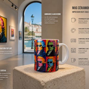 Peut inclure: Un mug en céramique blanc avec un motif pop art d'un homme portant des lunettes de soleil. Le mug a une capacité d'environ 325 ml et est présenté sur un bloc de pierre dans une galerie d'art.