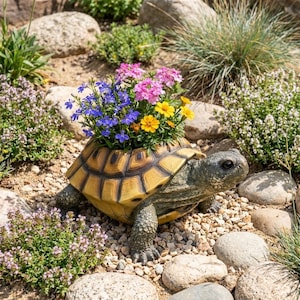 Puede incluir: Una maceta con forma de tortuga con un caparazón texturizado en tonos bronceado y marrón. La maceta está llena de un arreglo vibrante de pequeñas flores rosas, azules y amarillas, que contrastan con la piel escamosa de color gris oscuro de la tortuga.
