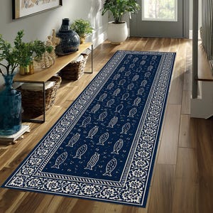 May include: A navy blue runner rug with a white fish pattern and decorative border. The rectangular rug is placed on a wooden floor in a hallway, adding a decorative element to the space.