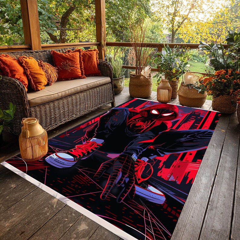 May include: A rectangular rug featuring a graphic of a superhero in a dynamic pose, set against a cityscape backdrop. The design incorporates bold red and black colors, with the superhero's suit and the city lights prominently displayed. The rug is placed on a wooden deck.