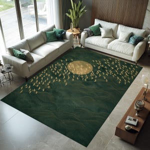 May include: A rectangular, dark green area rug with a gold sun and flock of birds design. The rug features a wavy pattern and is placed in a living room with white sofas and green accent pillows. The rug's dimensions are not visible.