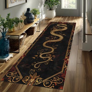 May include: A long rectangular runner rug featuring a black background with a large, winding gold snake illustration. The design includes intricate gold filigree, floral accents, and a decorative border, creating a detailed pattern across the surface.