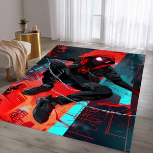May include: A rectangular area rug featuring a dynamic illustration of a superhero in a black suit with a red hood, set against a cityscape backdrop. The rug's color palette includes red, black, and teal, creating a vibrant and energetic design.