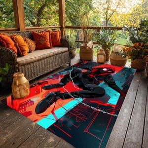 May include: A rectangular outdoor rug featuring a superhero graphic in black, red, and teal. The design depicts a figure in a dynamic pose against a cityscape backdrop. The rug is placed on a wooden deck.