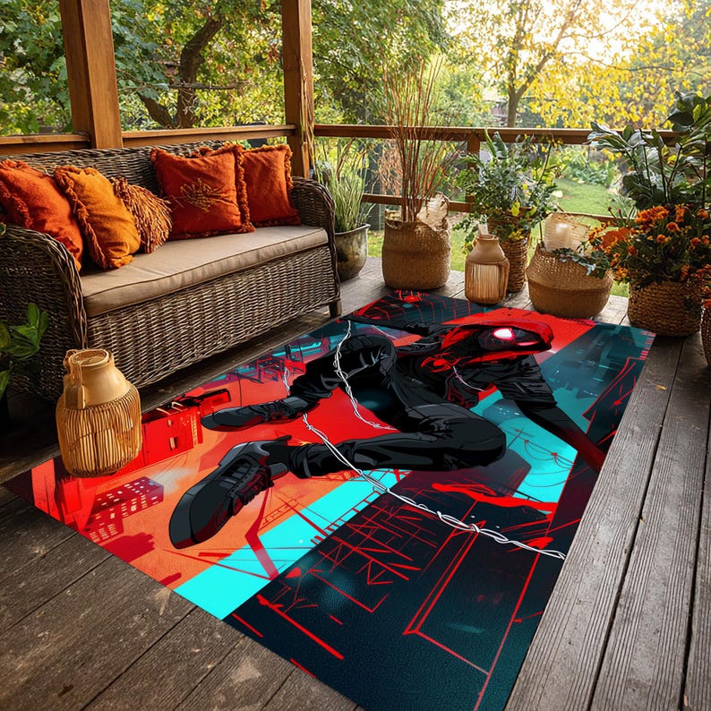 May include: A rectangular outdoor rug featuring a superhero graphic in black, red, and teal. The design depicts a figure in a dynamic pose against a cityscape backdrop. The rug is placed on a wooden deck.
