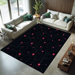 May include: A rectangular black area rug featuring a spiderweb design with numerous red spider eyes. The rug is placed in a living room setting with white sofas and green throw pillows.