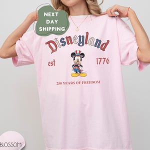 A woman wearing a pink t-shirt with a graphic of Mickey Mouse and text related to Disneyland.