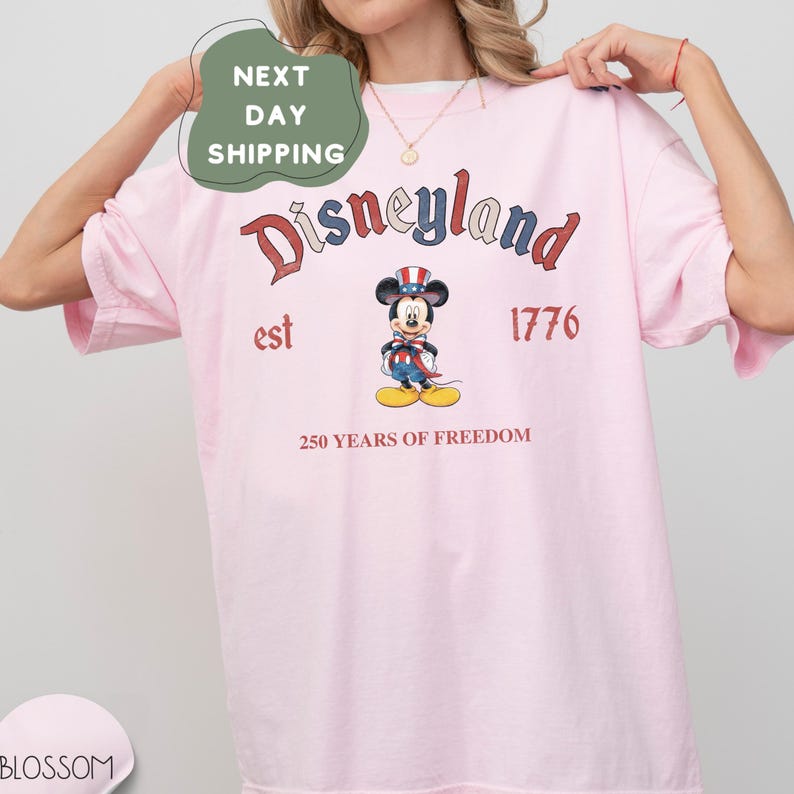 A woman wearing a pink t-shirt with a graphic of Mickey Mouse and text related to Disneyland.