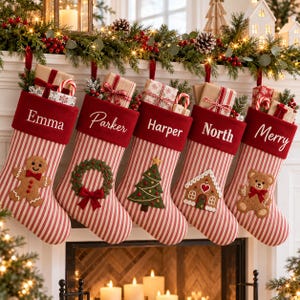 Può includere: Cinque calze natalizie a righe rosse e bianche con risvolti rossi, personalizzate con i nomi Emma, Parker, Harper, North e Merry. Le calze presentano ricami raffiguranti un omino di pan di zenzero, una ghirlanda, un albero, una casa e un orsetto.