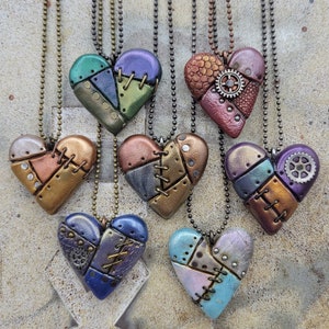 May include: Eight handmade heart-shaped pendants with a steampunk theme. Each pendant is made of polymer clay and features a different color combination and design. The pendants are all attached to silver chains.